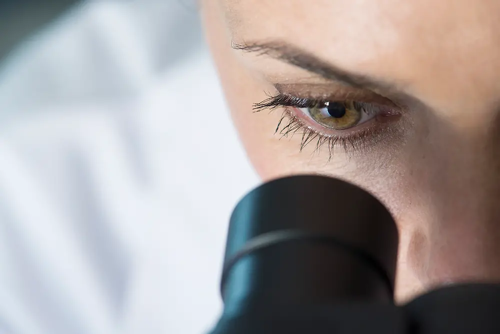 Oko ženy, ktorá sa pozerá do mikroskopu