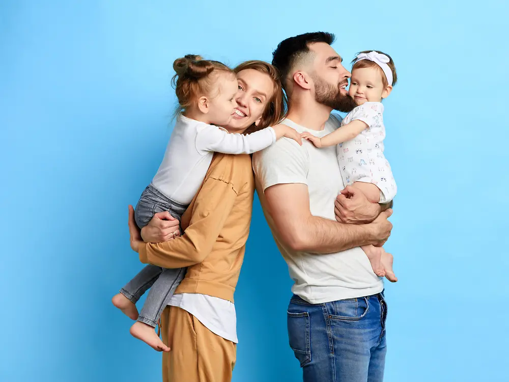 A family of 4 in front of a blue background.