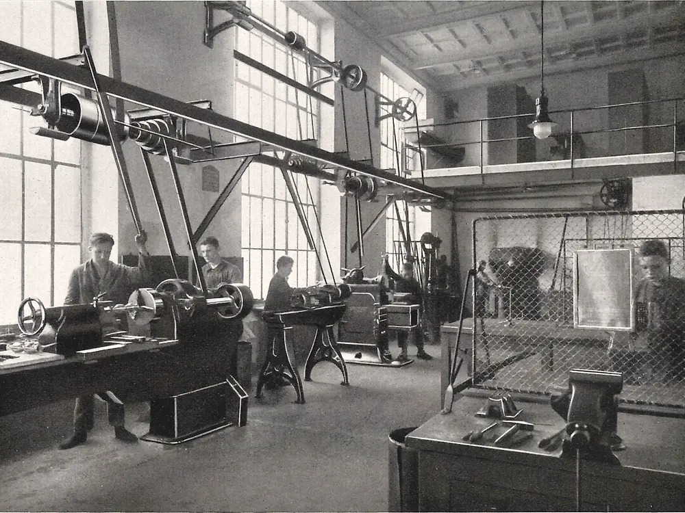 Učni pracujúci na strojoch v kovospracujúcej dielni.